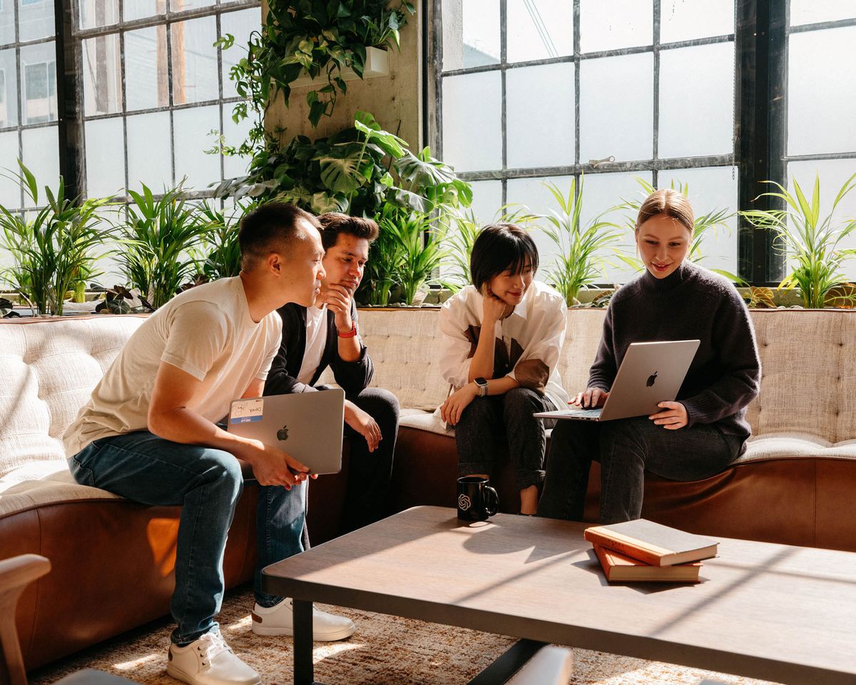 Team collaborating on laptops in a sunlit lounge