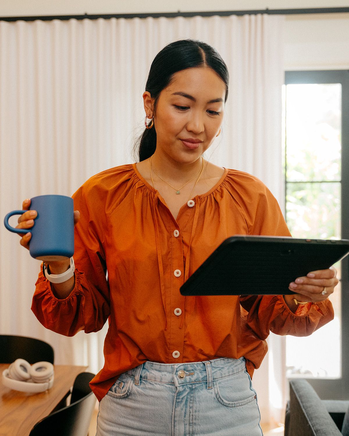 Person reviewing work on a tablet with coffee in hand